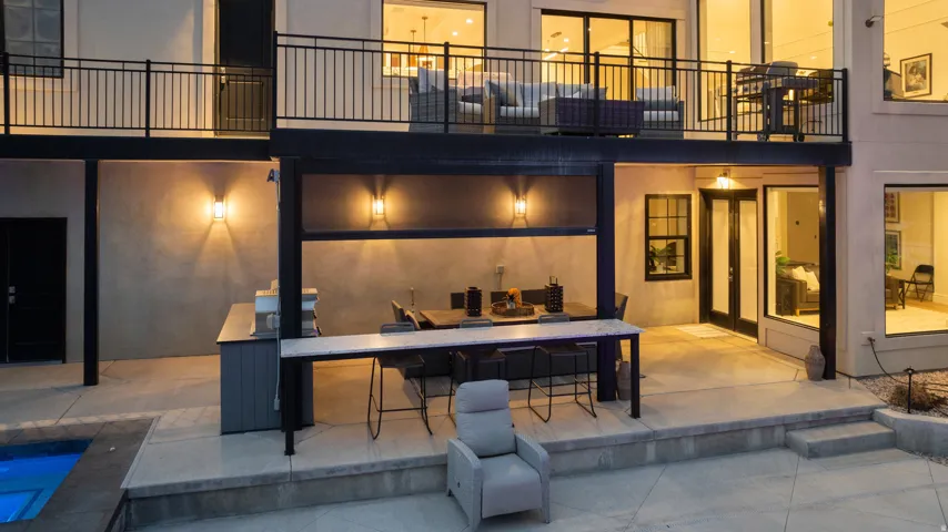 Outdoor kitchen and dining area with an integrated bar, concrete patio, and in-ground spa