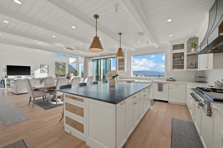 Open-concept living space featuring wood-finish flooring, a white coffered ceiling, and a kitchen island with a dark countertop