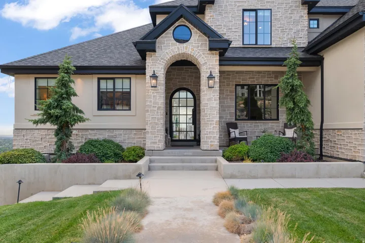 Stone and stucco exterior with dark trim accents and a prominent arched entryway