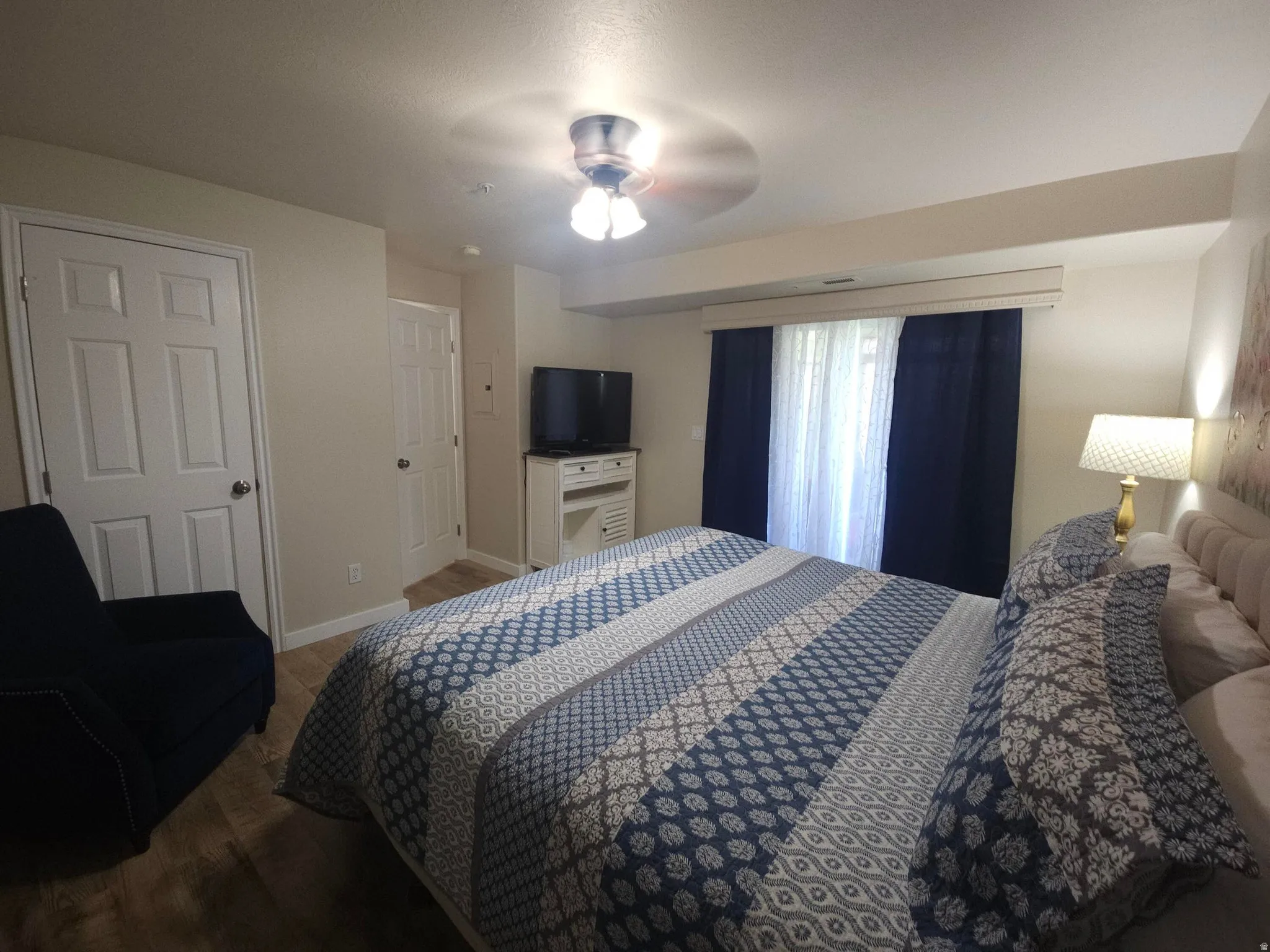 Interior room featuring wood-finish flooring, light-toned walls, and a ceiling fan with integrated lighting
