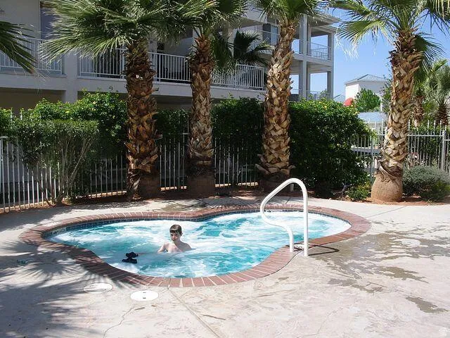 Heart-shaped spa with brick coping and a white handrail, surrounded by concrete decking