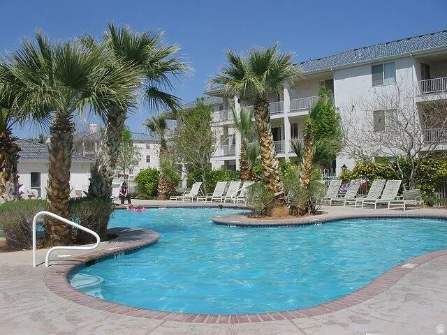 Expansive outdoor swimming pool featuring a curved design, brick coping, and surrounding concrete deck