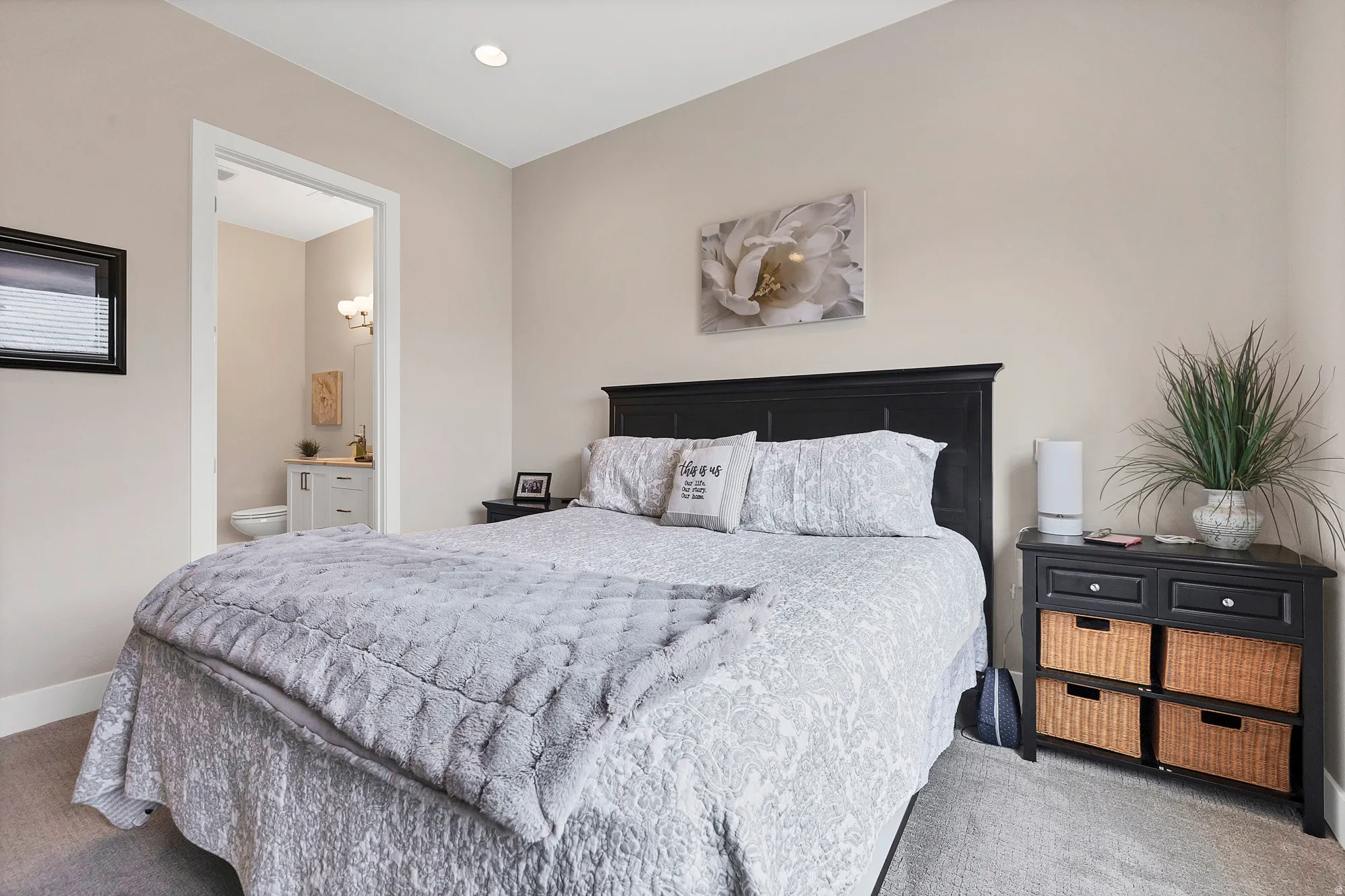 Recessed ceiling lighting illuminates a bedroom with neutral wall tones and plush carpeting
