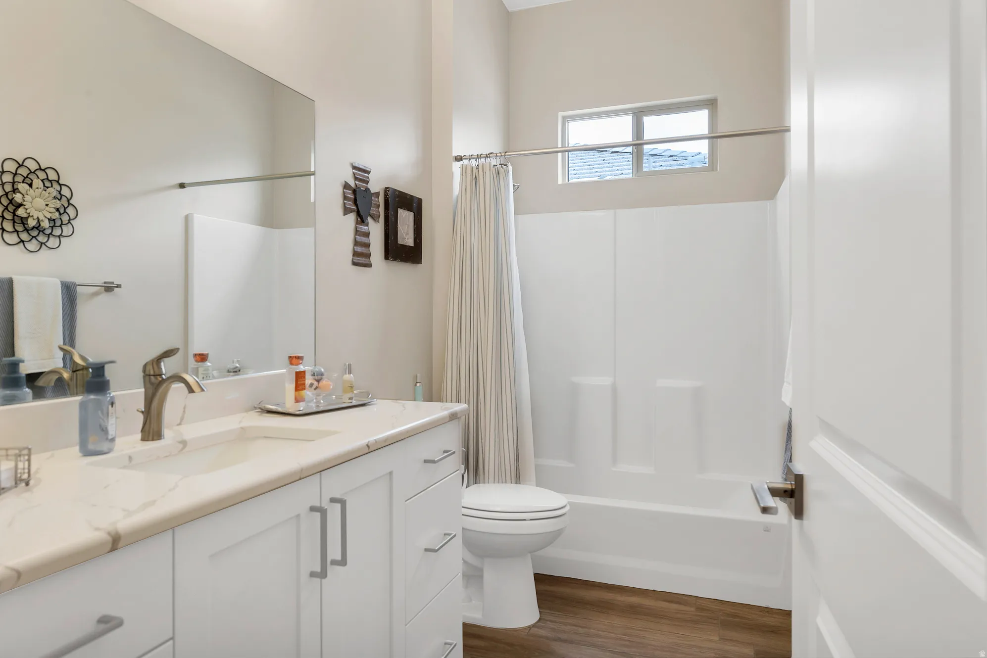 Bathroom featuring a spacious vanity with white cabinetry and a light-toned countertop, an integrated sink with a brushed nickel faucet, and a large mirror