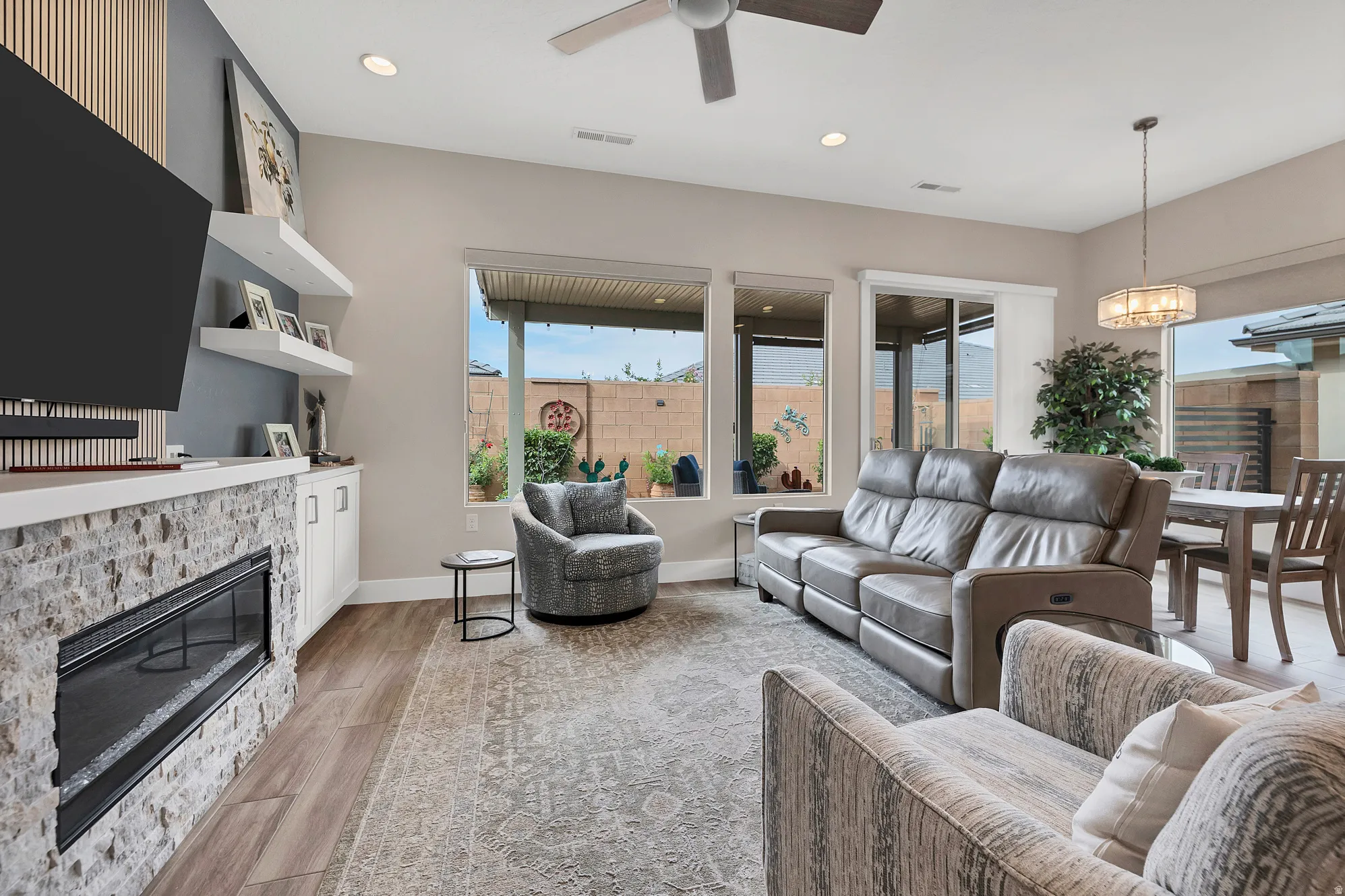 Living area featuring a floor-to-ceiling accent wall with vertical wood paneling and a linear electric fireplace with stone surround