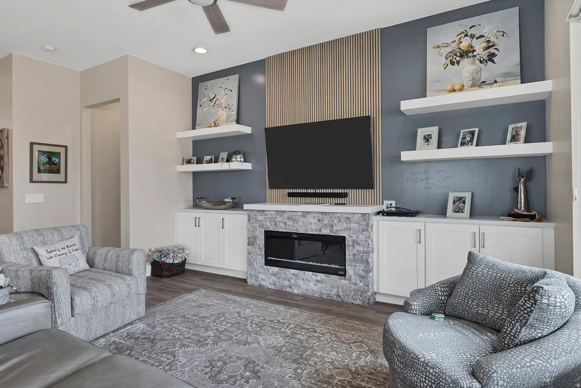 Living area featuring a modern electric fireplace with a stacked stone surround, flanked by white built-in cabinetry with counter space