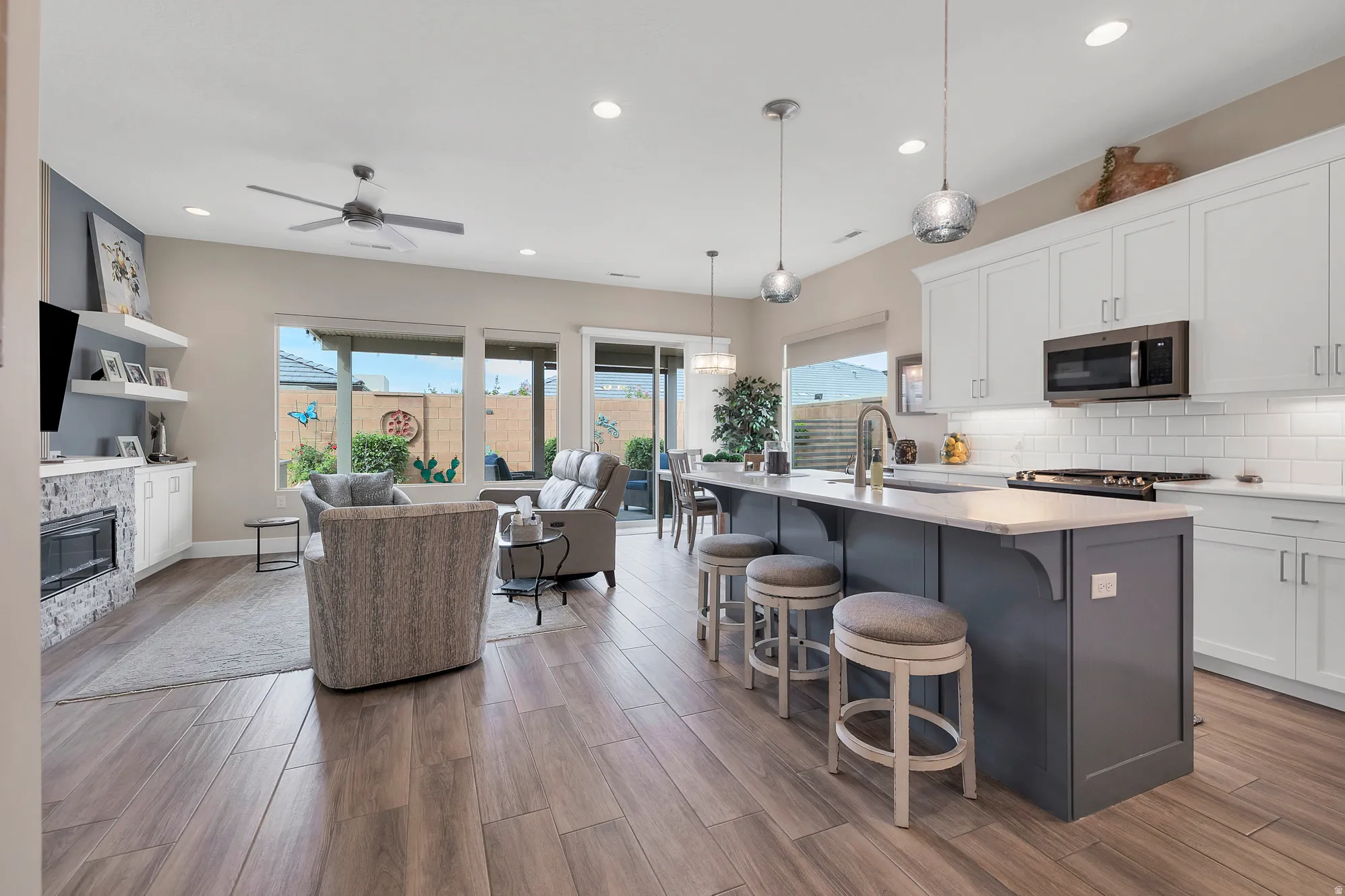 Open-concept living space featuring wood-finish flooring, a contemporary ceiling fan, and recessed lighting