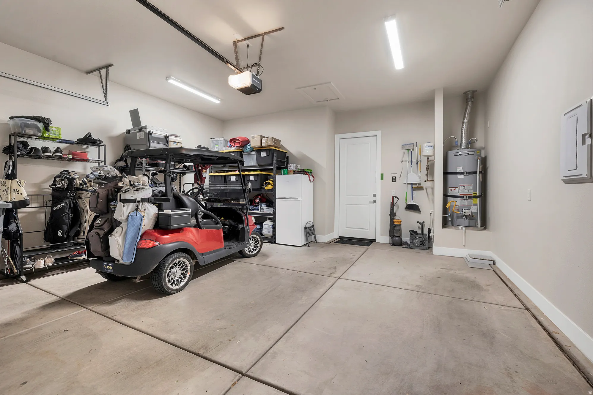 Spacious garage featuring a concrete floor, overhead lighting, and an internal access door