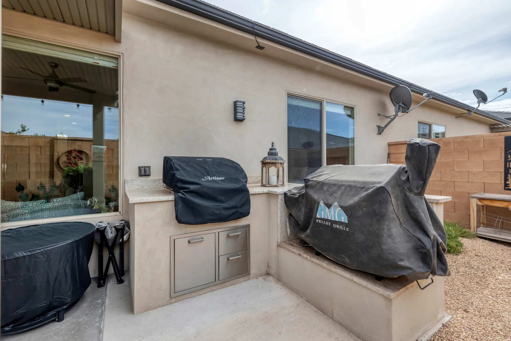 Outdoor kitchen featuring built-in stainless steel cabinetry, a light-colored countertop, and a stucco finish