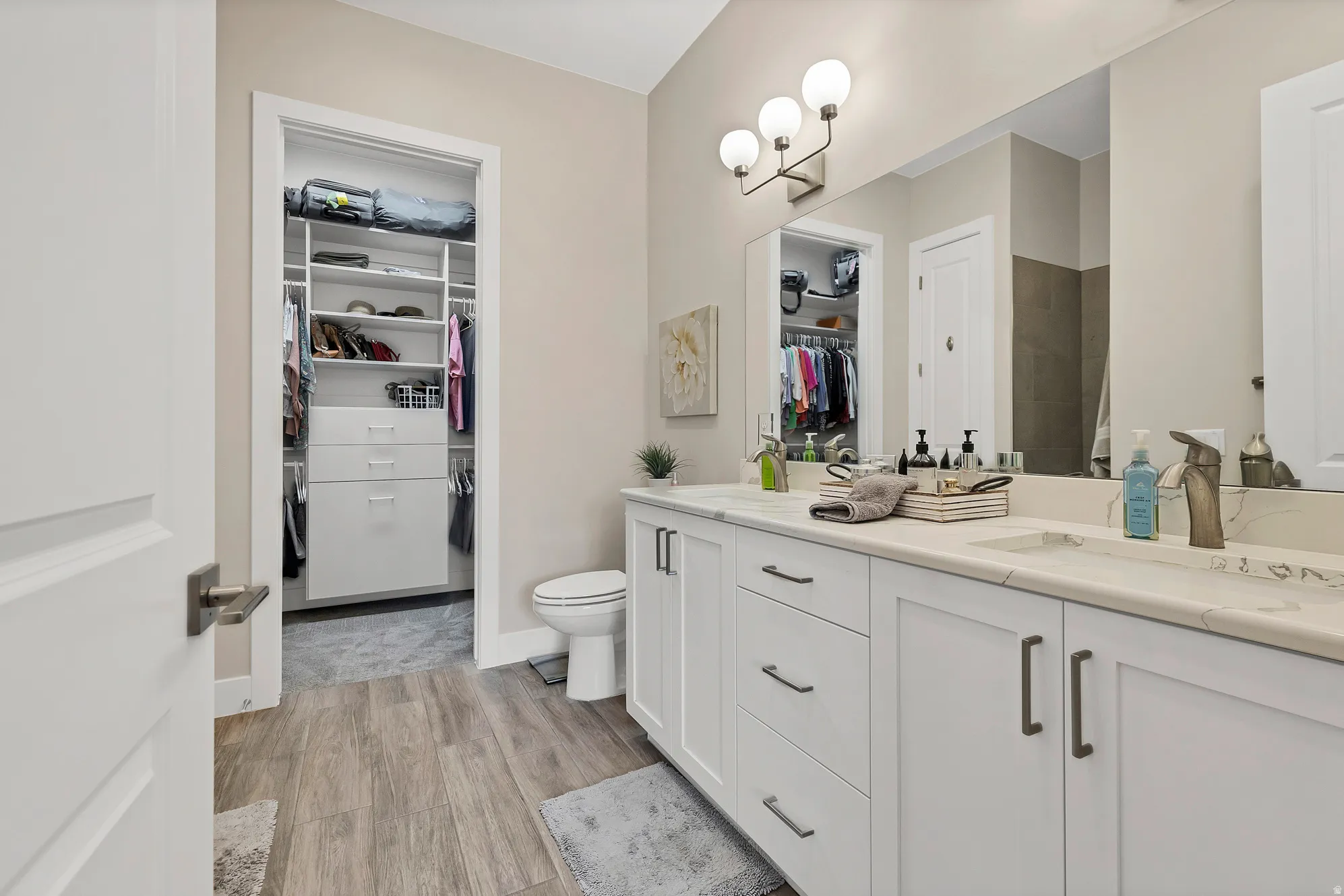 Bathroom featuring a dual vanity with white cabinetry, light-toned countertops, and integrated sinks