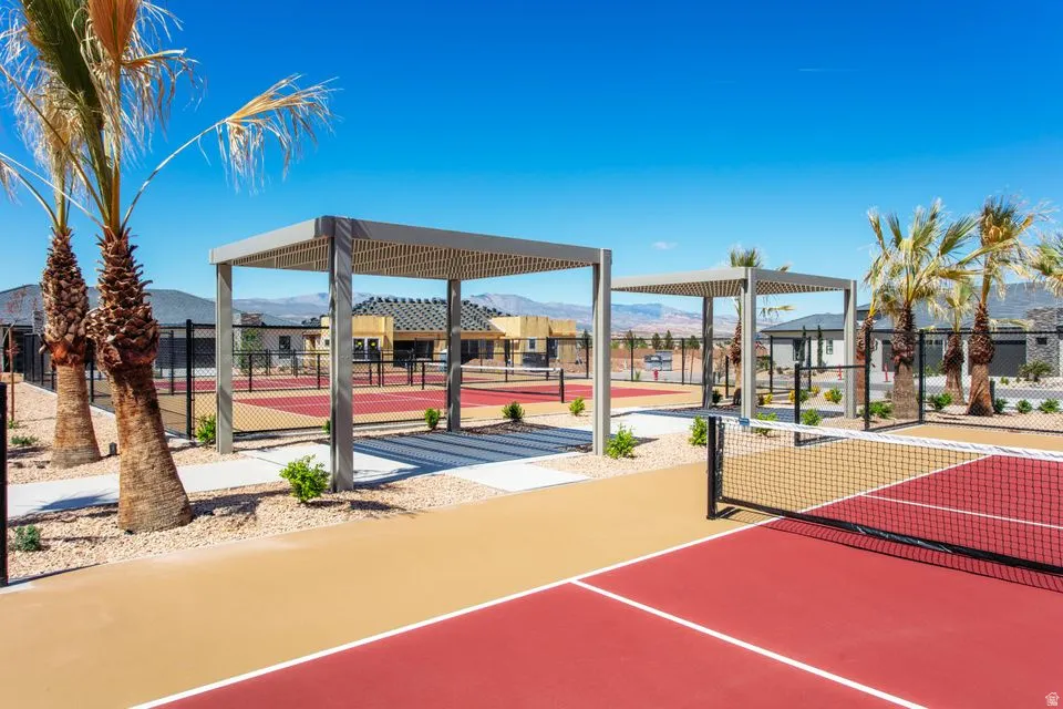 Outdoor recreational courts with red and tan surfacing, multiple shade pergolas, and established palm trees