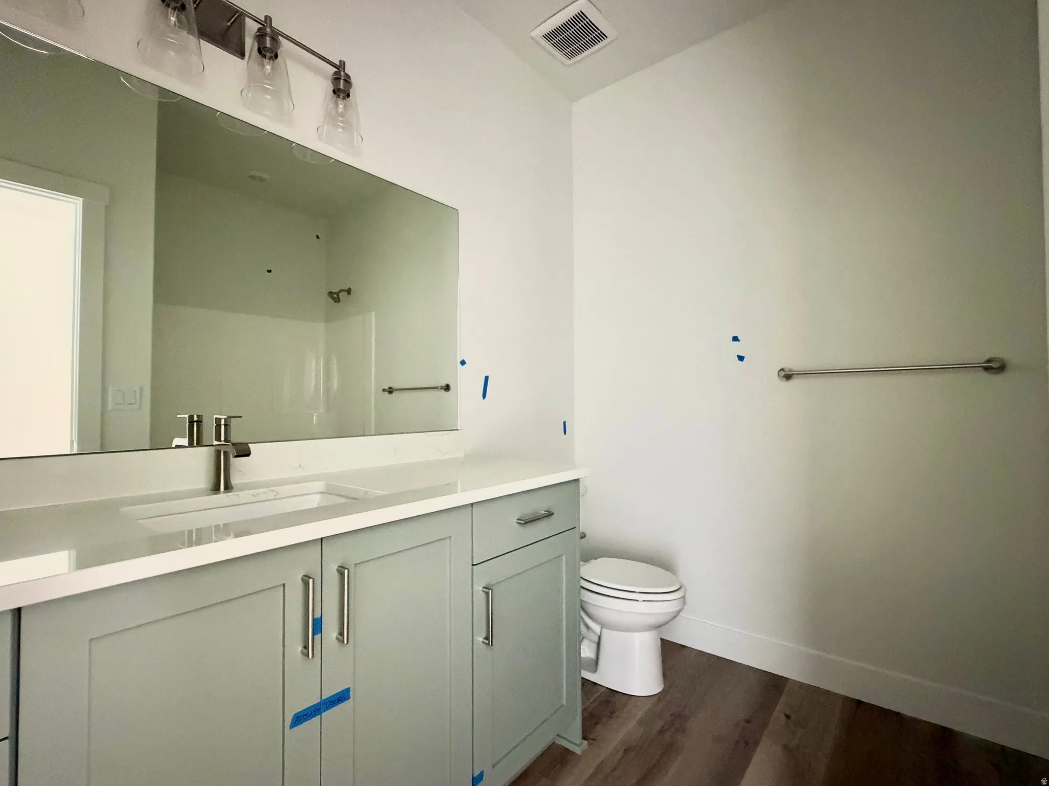 Modern bathroom featuring a broad vanity with light green cabinetry, a white countertop, and an undermount sink