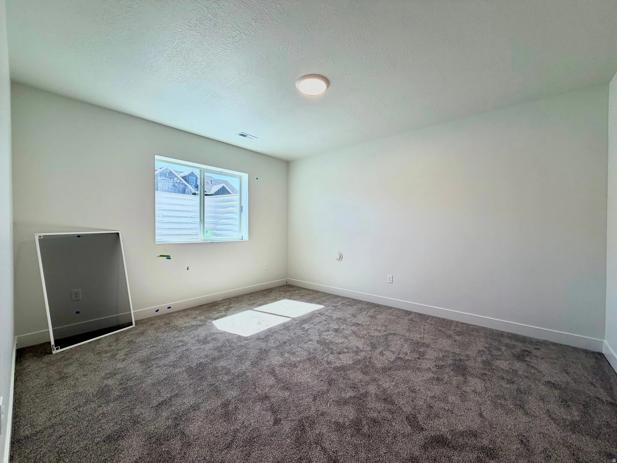 Carpeted interior space with a single window and recessed lighting
