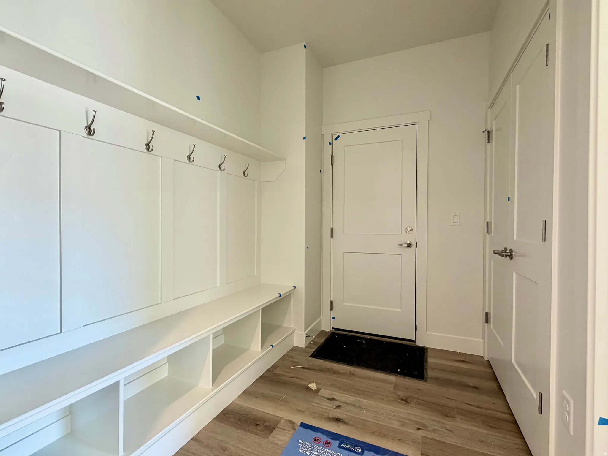 Built-in mudroom features paneling, coat hooks, and integrated storage cubbies