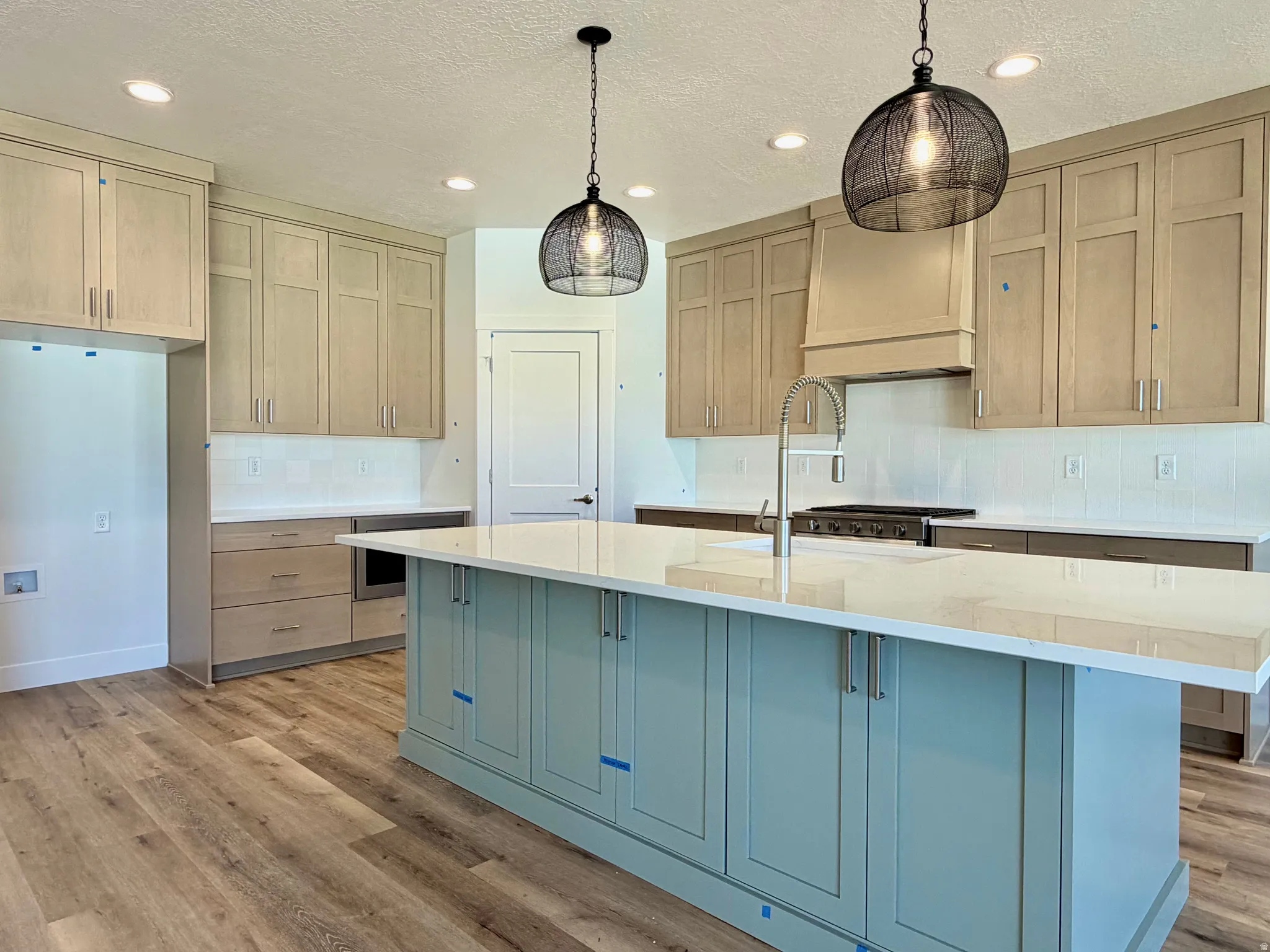 Kitchen island with a light-colored countertop, complemented by two distinctive wire-cage pendant lights and recessed ceiling lighting