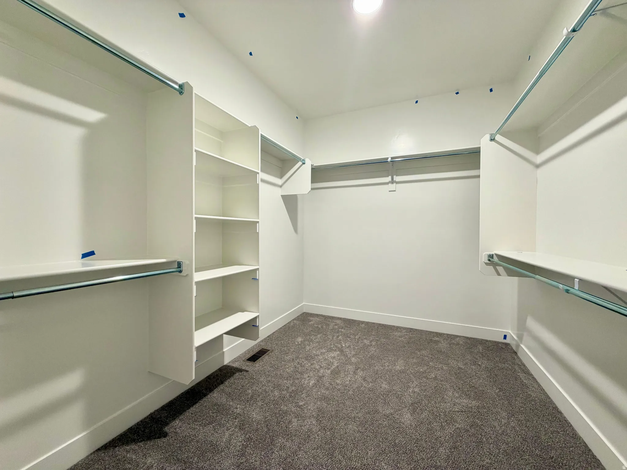 Walk-in closet featuring built-in shelving, hanging rods, recessed lighting, and carpet flooring