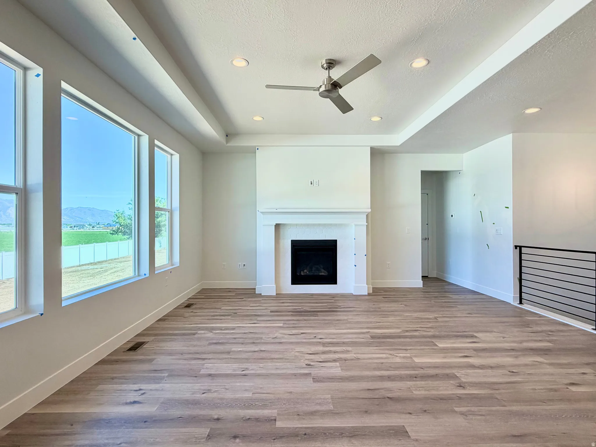 Open concept living space featuring wood-finish flooring, a tray ceiling, and a contemporary ceiling fan