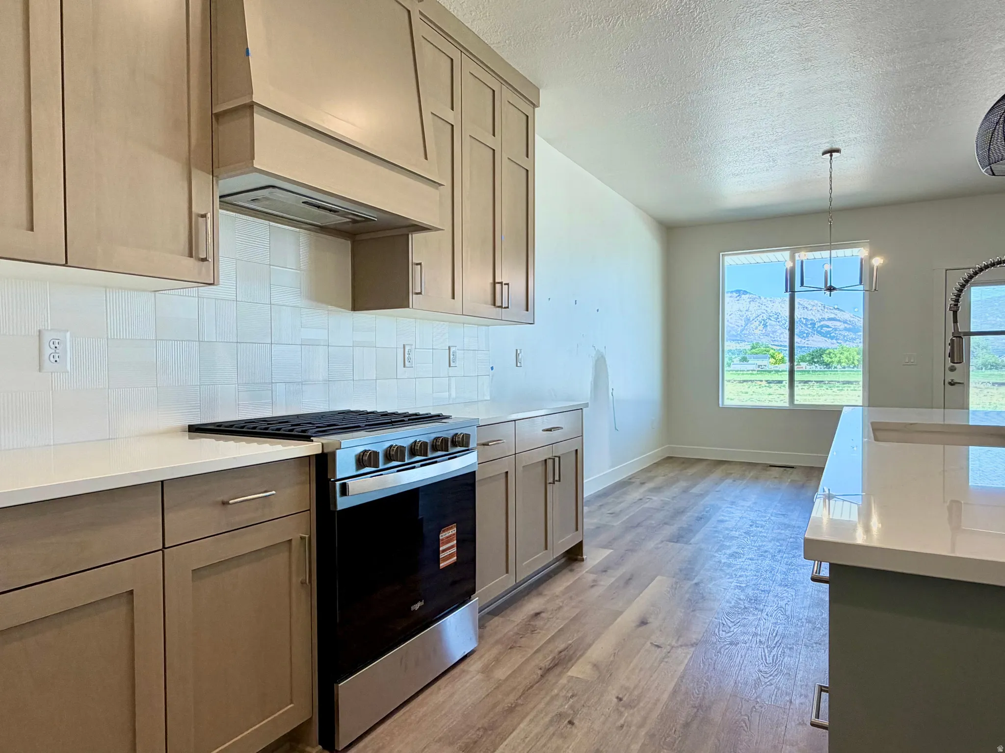 Modern kitchen featuring light wood-finish cabinetry, a stainless steel range, and a white tile backsplash