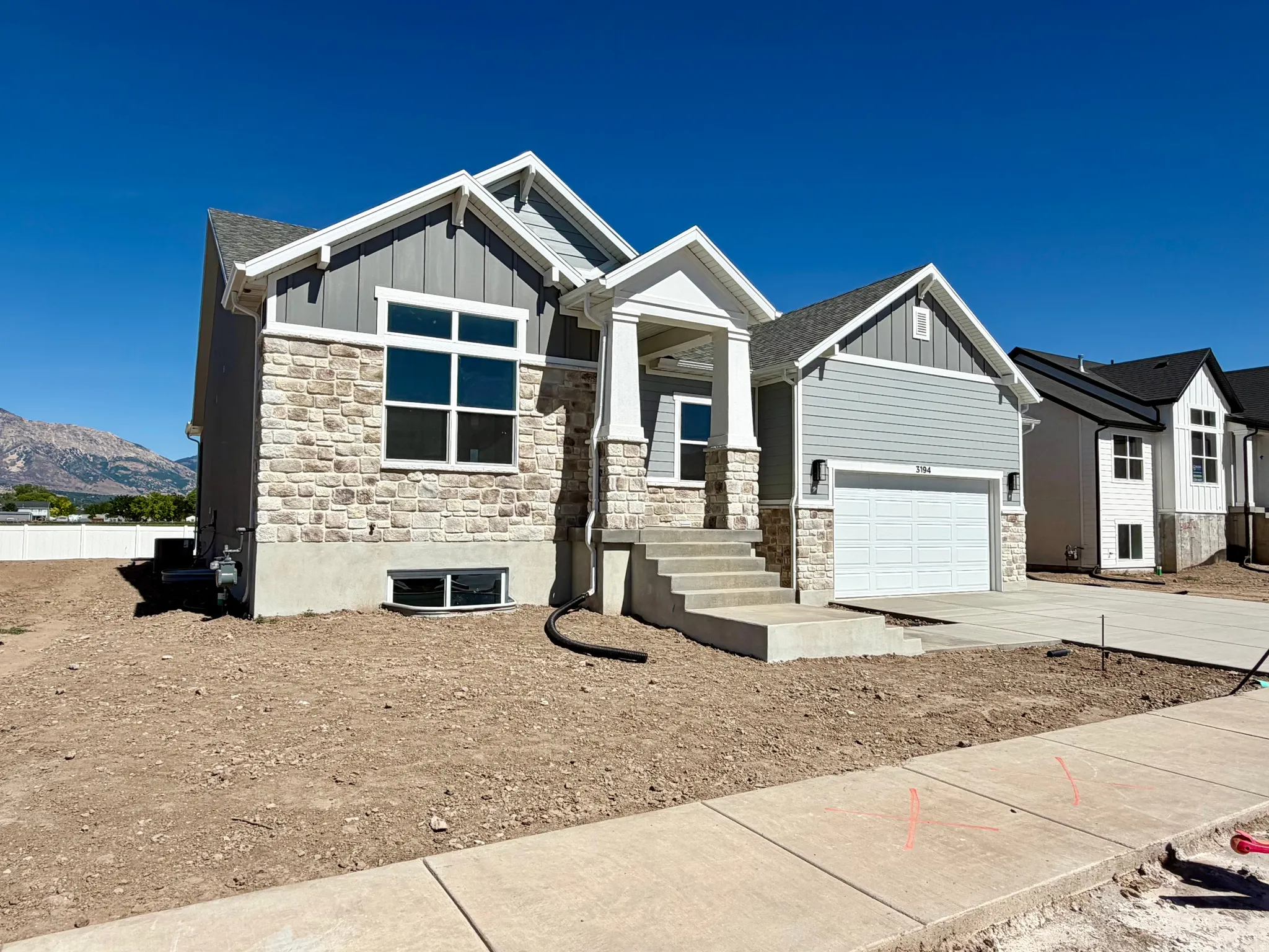 Contemporary exterior featuring light grey siding and stone veneer accents