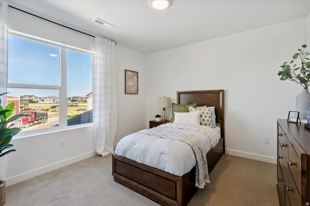 Bedroom featuring a large window, neutral carpet flooring, white walls, a single ceiling light fixture, and white baseboards