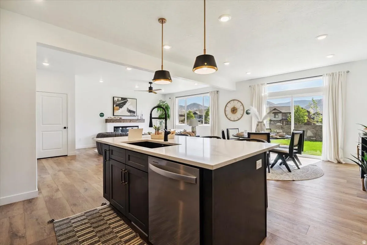 Kitchen island with dark cabinetry, integrated sink, and stainless steel dishwasher