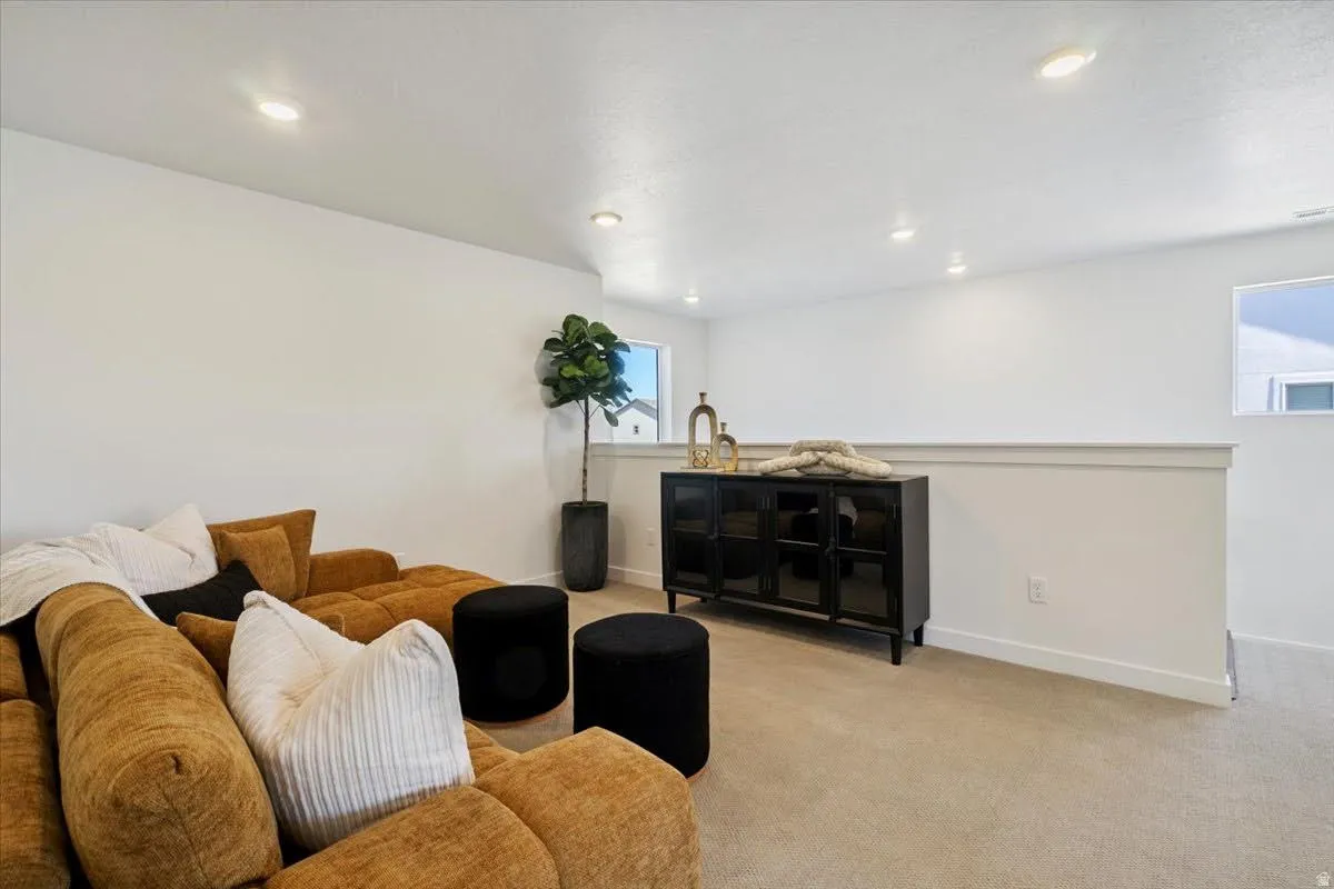 Carpeted loft area featuring recessed lighting, a half-wall partition, and a single window