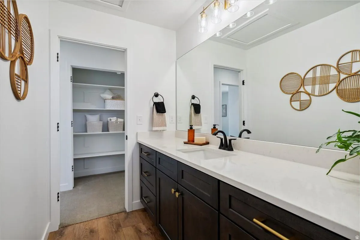 Bathroom vanity featuring a single undermount sink, a white countertop, and dark wood-finish cabinetry with brass hardware