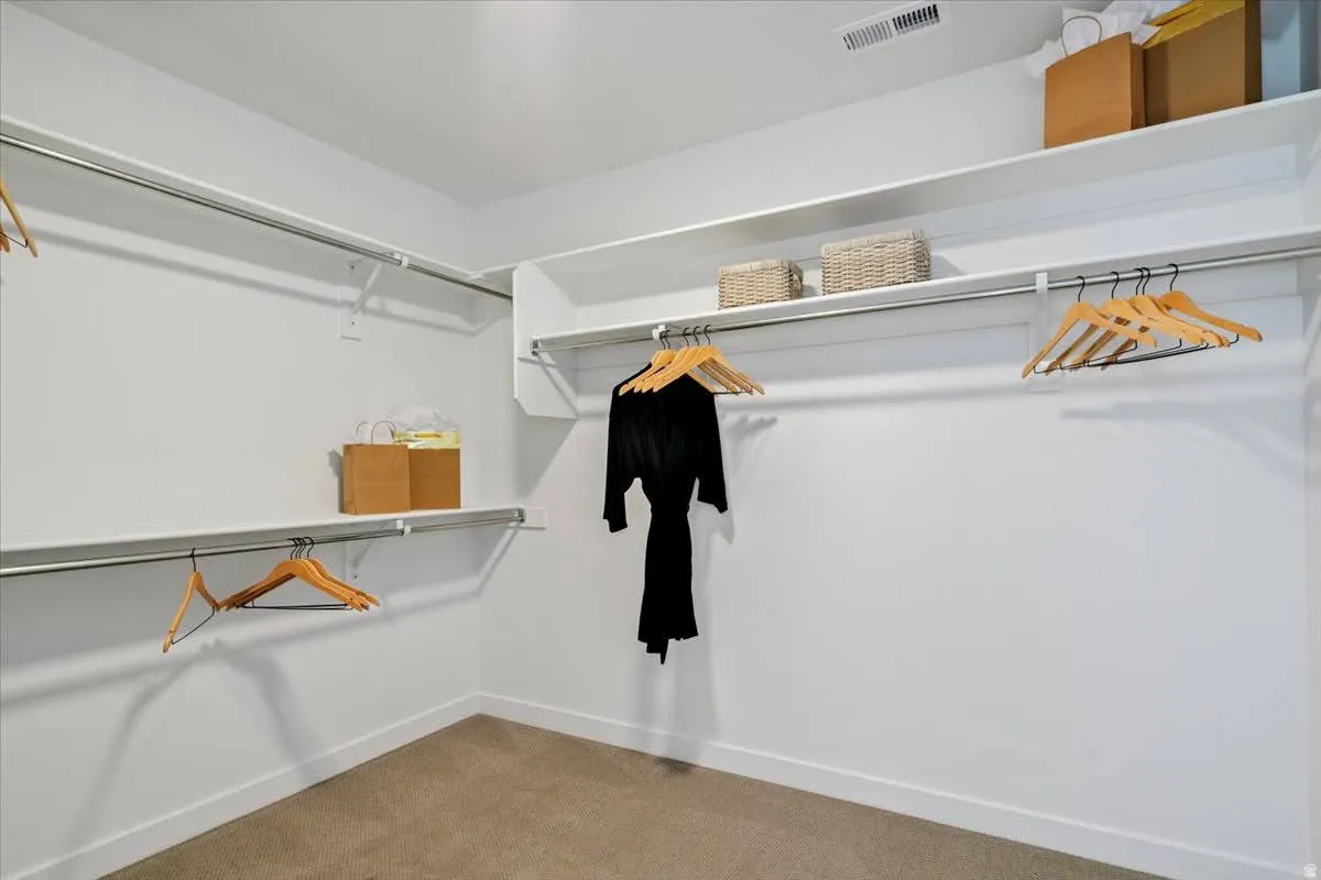 Walk-in closet featuring white shelving, chrome hanging rods, recessed lighting, and carpet flooring