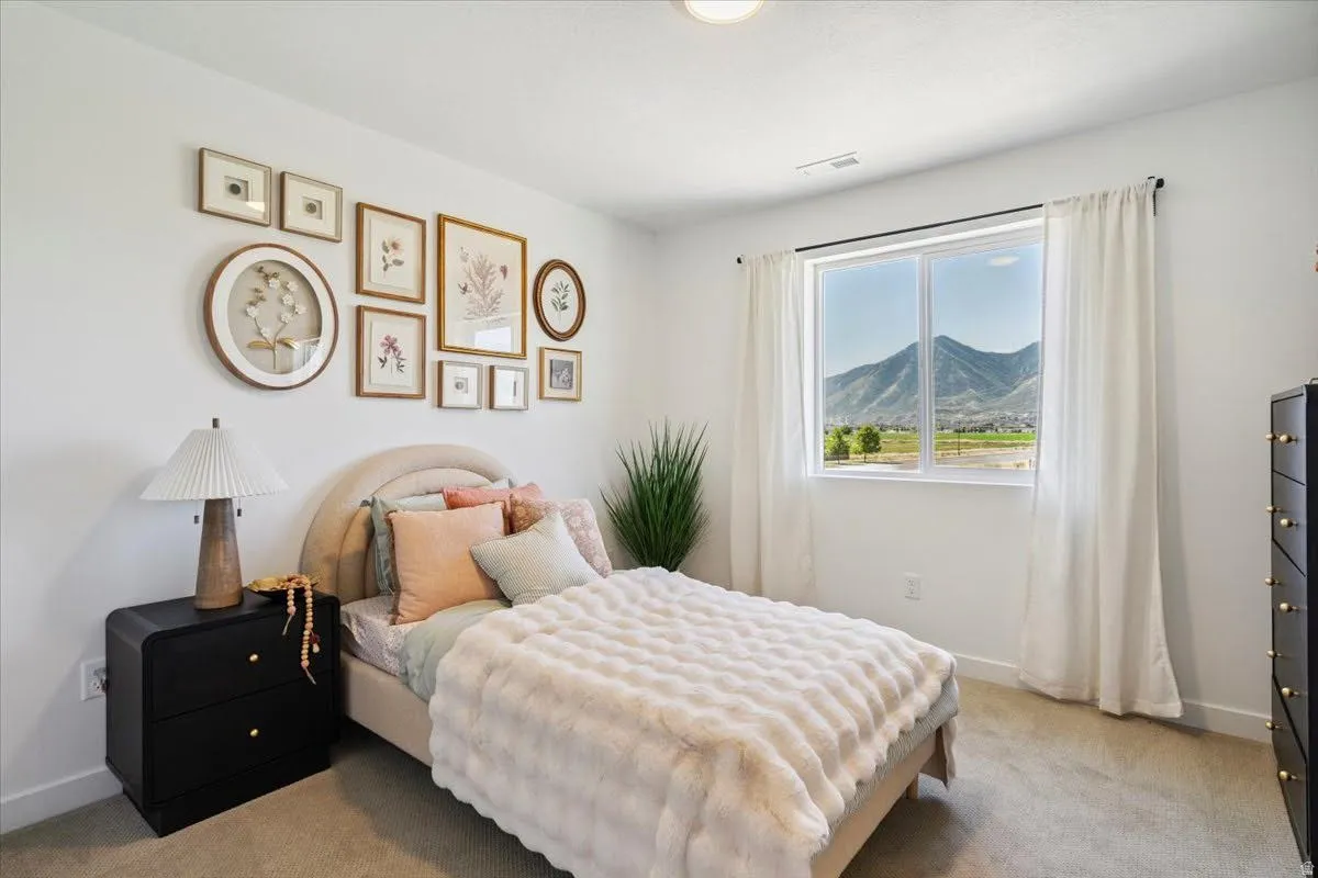 Carpeted bedroom featuring a large window with a mountain backdrop, white walls, and a ceiling-mounted light fixture