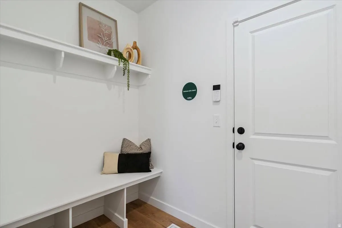 Entryway featuring built-in bench seating with storage cubbies, an overhead display shelf, and wood-finish flooring