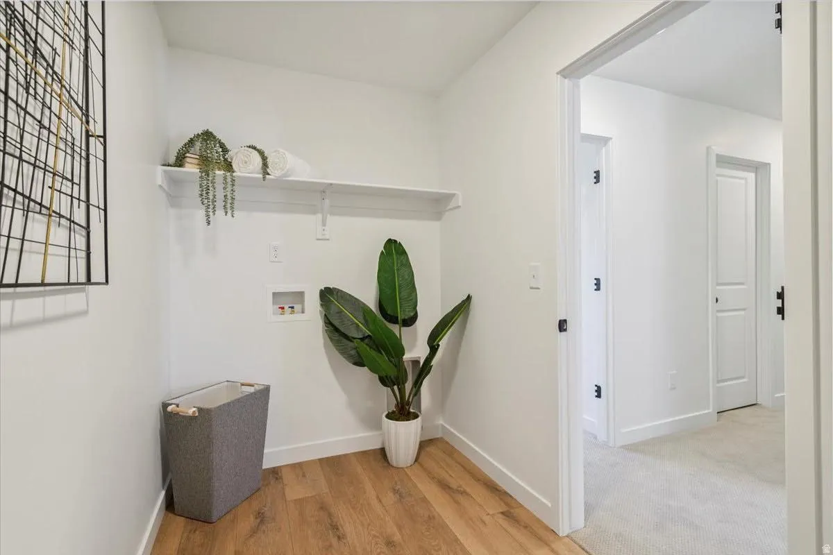 Dedicated utility space featuring wood-finish flooring, white walls, and a built-in shelving unit