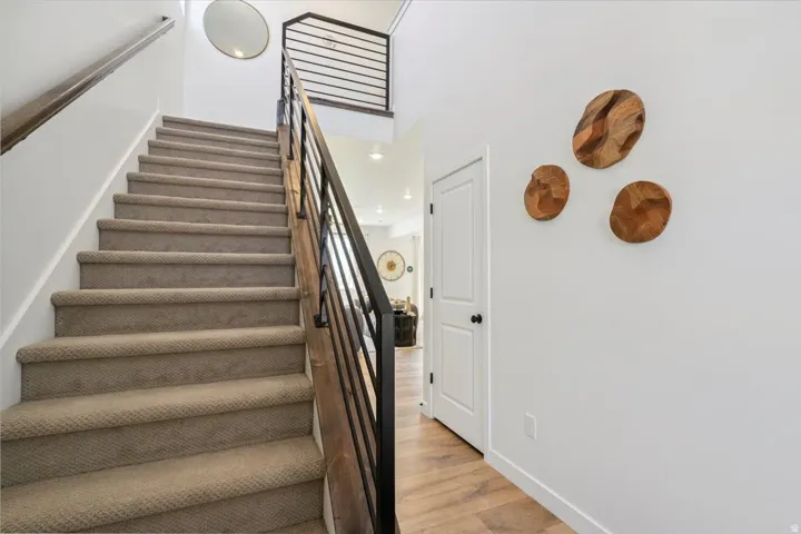 Carpeted staircase with dark wood handrail and black metal balusters
