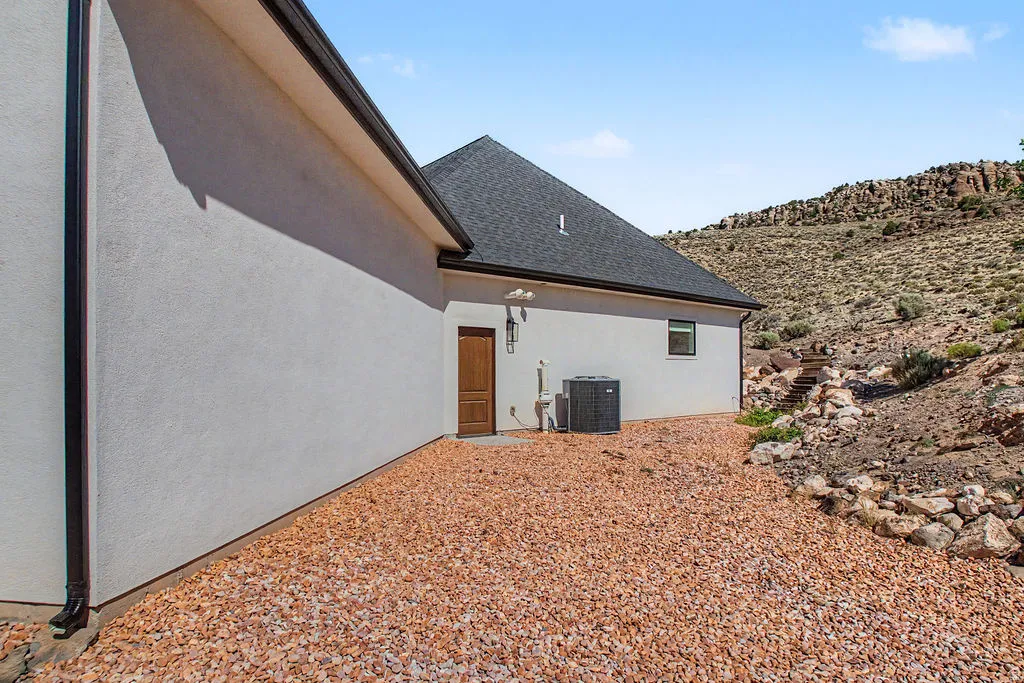 Stucco exterior with dark trim and a shingle roof