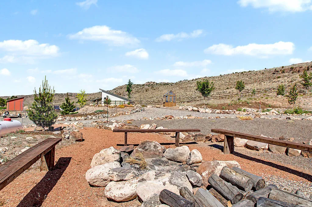 Outdoor gathering area featuring a rock-lined fire pit and multiple wooden benches