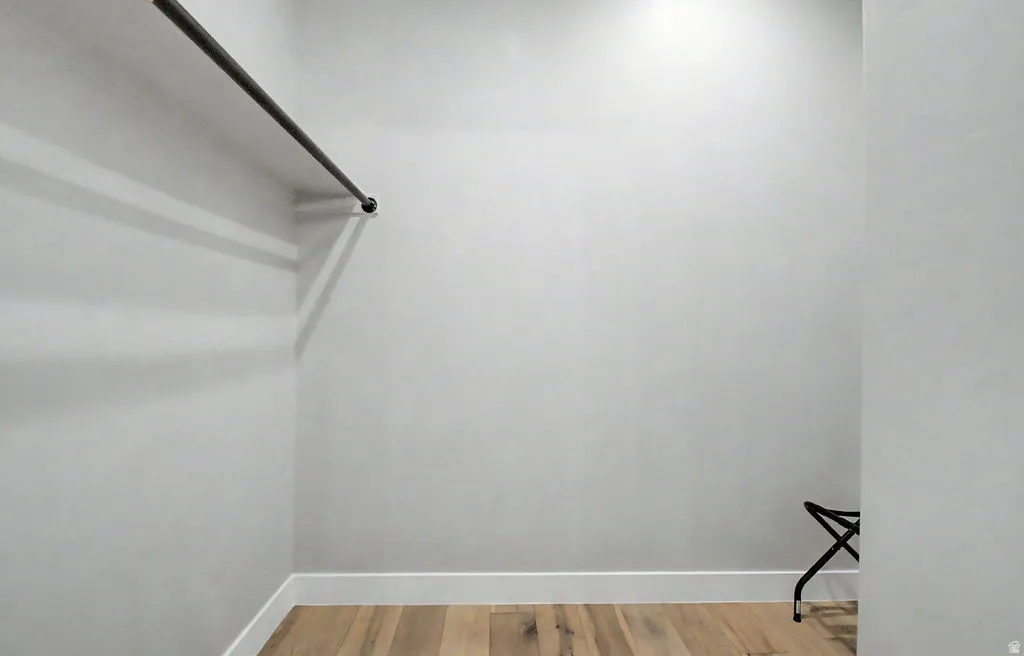 Closet featuring a single hanging rod, hardwood flooring, and white baseboards