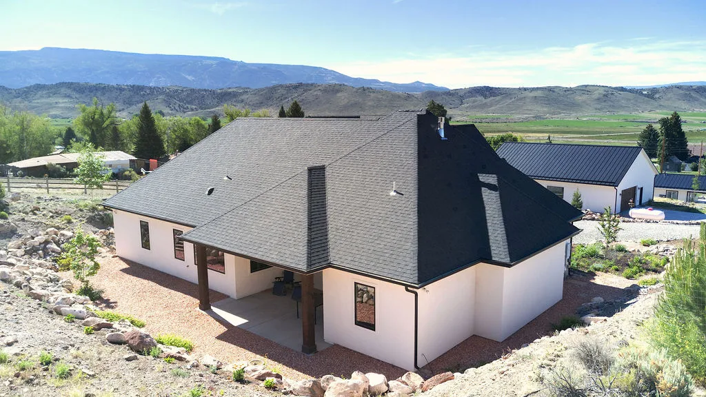 White stucco exterior with a dark asphalt shingle roof