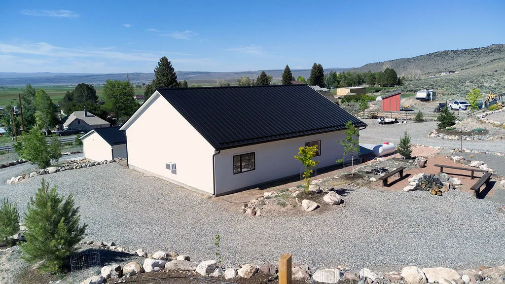 Single-story home featuring a black metal roof and light-colored siding