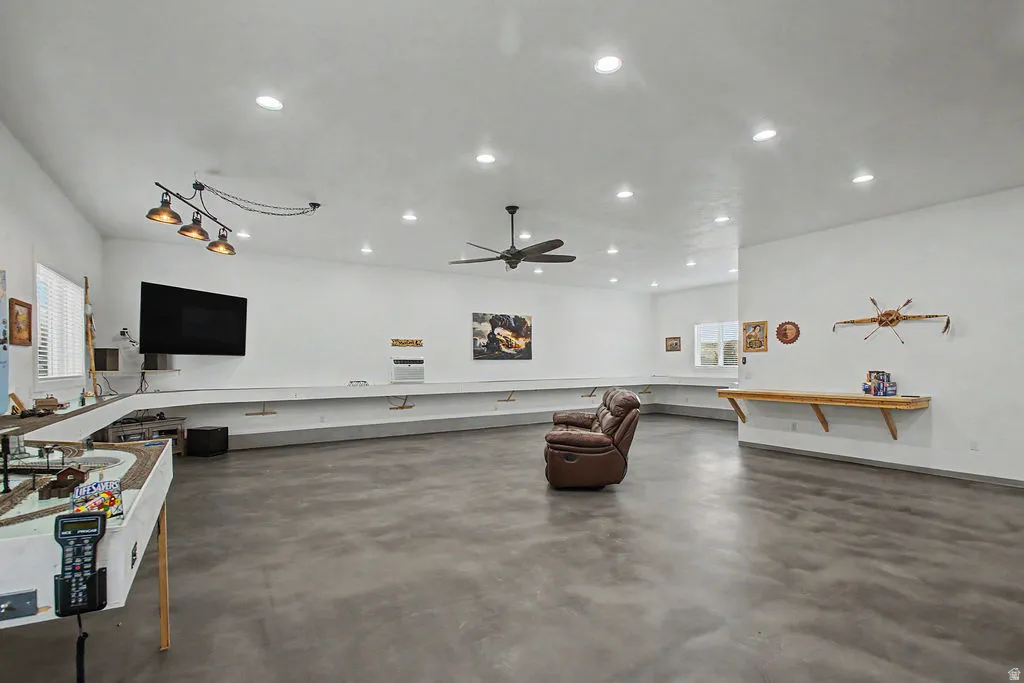 Spacious detatched shop featuring polished concrete flooring, extensive built-in shelving, recessed lighting, and a ceiling fan