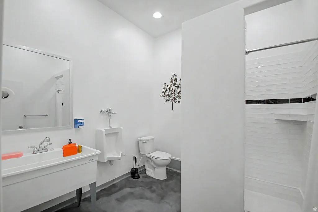 Bright bathroom featuring a utility sink, wall-mounted urinal, and a toilet