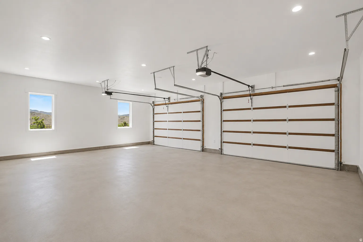 Spacious two-car garage featuring automatic openers, recessed lighting, and dual windows