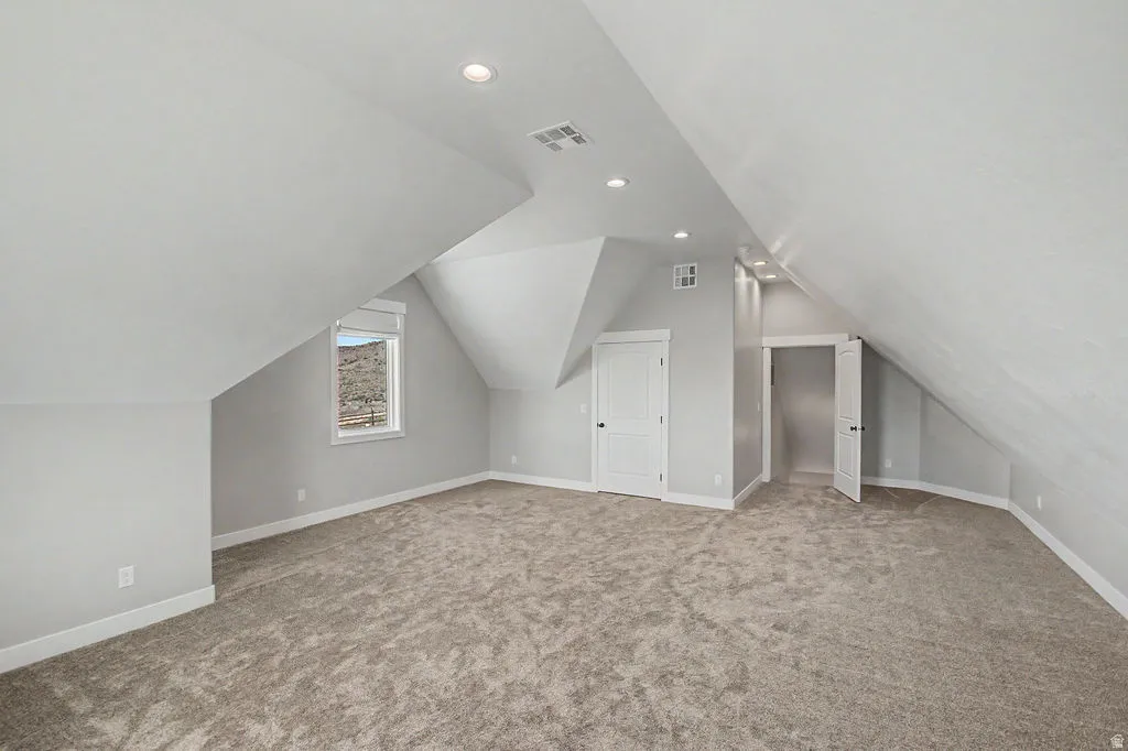 Bonus Room Spacious room featuring sloped ceilings, recessed lighting, neutral-toned carpet, a window with mountain scenery, and two panel doors