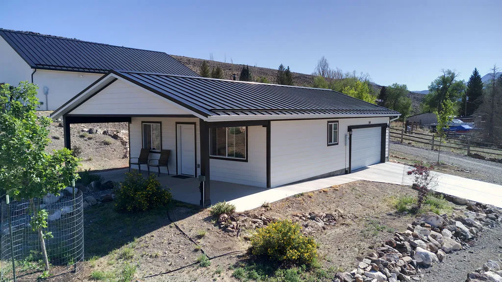 Contemporary white siding exterior with dark trim and a black metal roof