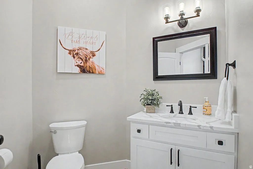 1/2 bath Vanity area featuring a crisp white cabinet with black hardware, a stone-finish countertop, and a rectangular sink with a matte black faucet