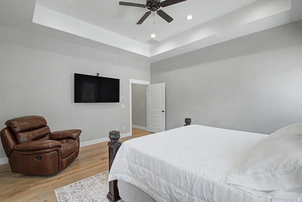 Bedroom featuring a tray ceiling with recessed lighting and a ceiling fan