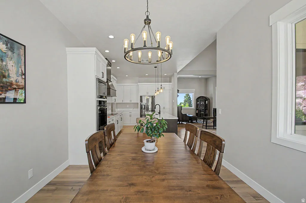 Spacious dining area featuring wood-finish flooring and a contemporary chandelier