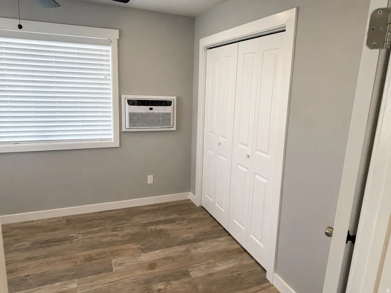 Room featuring wood-finish flooring, light grey painted walls, and white baseboards