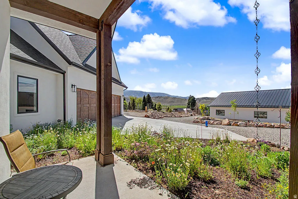 Covered patio with exposed wood beams, featuring a stucco exterior and a concrete patio slab