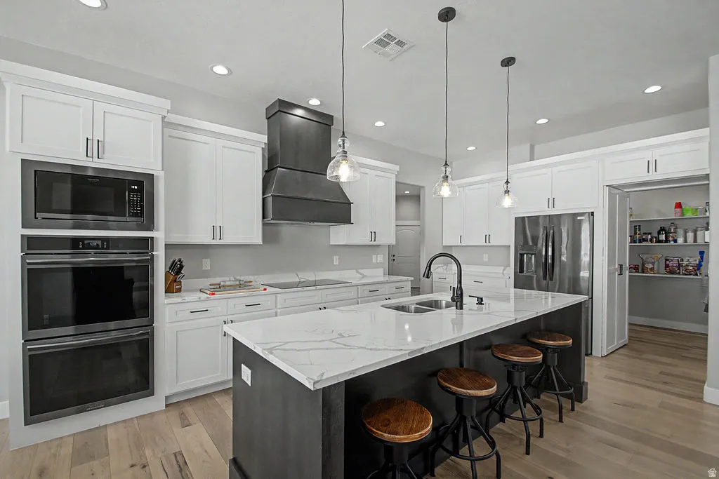 Bright kitchen featuring an expansive center island with seating, a double basin sink, and pendant lighting