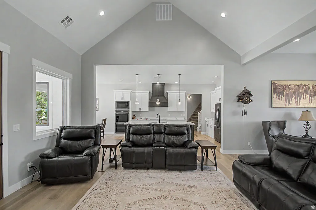 Vaulted ceiling living area featuring light wood-finish flooring and recessed lighting
