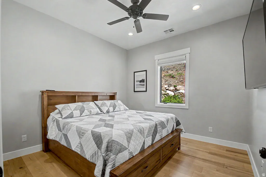 Room featuring light wood-finish flooring, a contemporary ceiling fan, recessed lighting, and a window with a roller shade